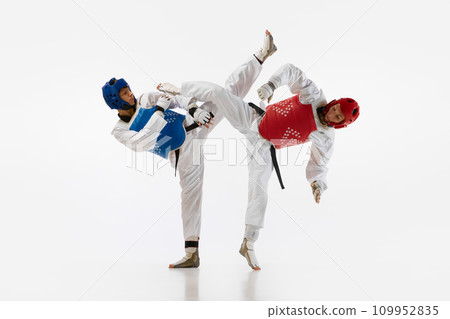 Dynamic image of young men, taekwondo athletes in kimono and helmets training isolated over white background. Martial arts, combat sport Dynamic image of young men, taekwondo athletes in kimono and helmets training isolated over white background. Martial arts, combat sport 109952835
