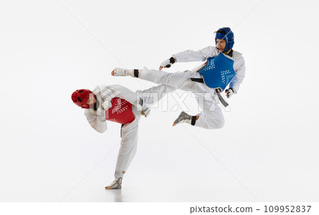 Dynamic image of young men, taekwondo athletes in kimono and helmets training isolated over white background. Martial arts, combat sport 109952837