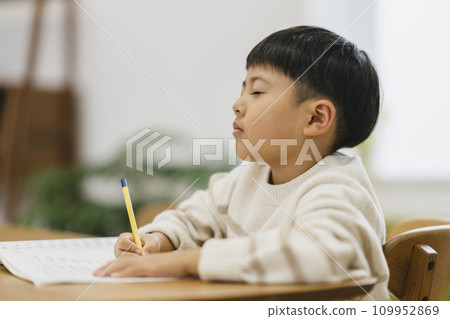 Elementary school boy thinking with his eyes closed while studying Elementary school boy thinking with his eyes closed while studying 109952869