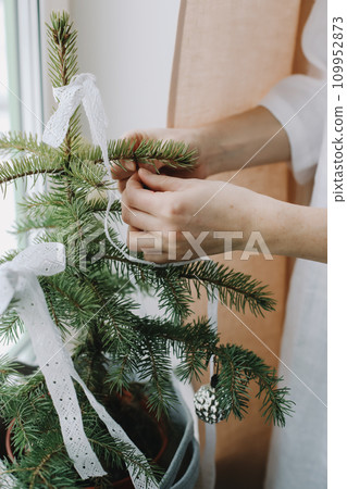 Woman hands decorating christmas tree. Atmospheric time. Holiday, Christmas and New Year family celebration concept. 109952873