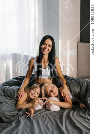 Happy young mom with two daughters resting on the bed 109952938