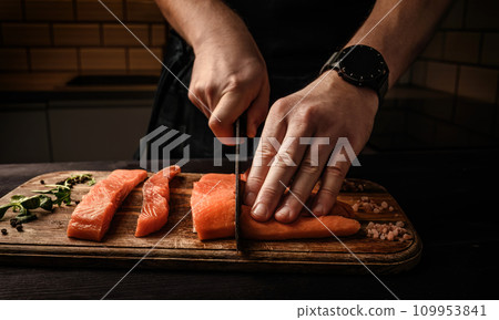Mle cutting red Salmon fish on a cutting board Mle cutting red Salmon fish on a cutting board 109953841