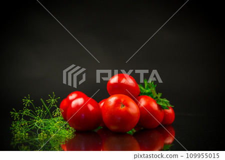 Ripe red tomatoes with greens on black background. 109955015