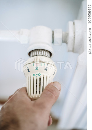 Radiator thermostat and hand. Heating house in winter. Savings on heating concept 109956462