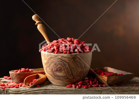 Dried goji berries in wooden bowl on a brown background. 109956469