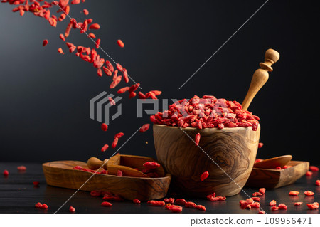 Dried goji berries in wooden bowl on a black background. 109956471