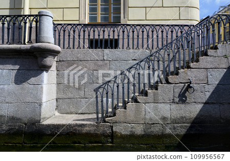 Granite steps with openwork railings of 18 century leading to the Fontanka River in St. Petersburg Granite steps with openwork railings of 18 century leading to the Fontanka River in St. Petersburg 109956567