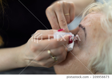 The beautician works without gloves and has her nails painted red. The beautician works without gloves and has her nails painted red. 109956673