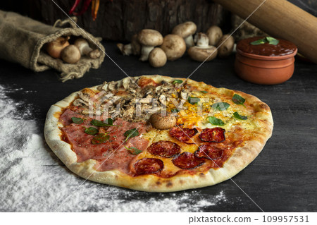 Italian Pizza Four Seasons (Pizza Quattro Stagioni) with different ingredients on the wooden table in the kitchen Italian Pizza Four Seasons (Pizza Quattro Stagioni) with different ingredients on the wooden table in the kitchen 109957531