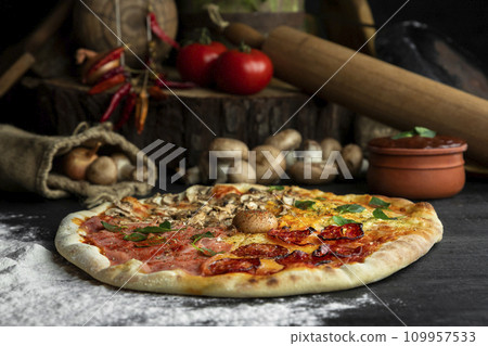 Italian Pizza Four Seasons (Pizza Quattro Stagioni) with different ingredients on the wooden table in the kitchen Italian Pizza Four Seasons (Pizza Quattro Stagioni) with different ingredients on the wooden table in the kitchen 109957533