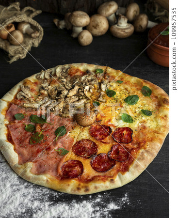 Italian Pizza Four Seasons (Pizza Quattro Stagioni) with different ingredients on the wooden table in the kitchen Italian Pizza Four Seasons (Pizza Quattro Stagioni) with different ingredients on the wooden table in the kitchen 109957535
