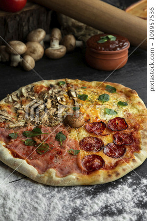 Italian Pizza Four Seasons (Pizza Quattro Stagioni) with different ingredients on the wooden table in the kitchen Italian Pizza Four Seasons (Pizza Quattro Stagioni) with different ingredients on the wooden table in the kitchen 109957536