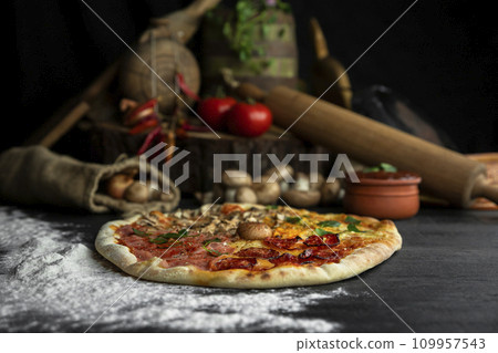 Italian Pizza Four Seasons (Pizza Quattro Stagioni) with different ingredients on the wooden table in the kitchen 109957543
