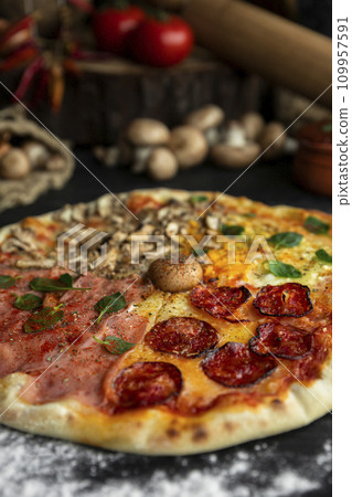 Italian Pizza Four Seasons (Pizza Quattro Stagioni) with different ingredients on the wooden table in the kitchen Italian Pizza Four Seasons (Pizza Quattro Stagioni) with different ingredients on the wooden table in the kitchen 109957591