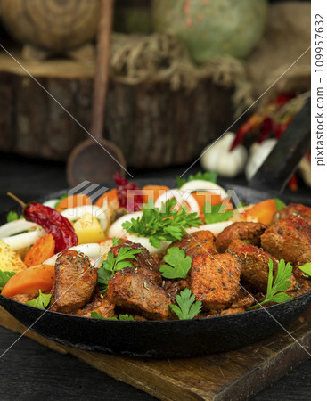 Stew with meat and vegetables in black iron dish. Traditional gourmet goulash in a rustic kitchen 109957632