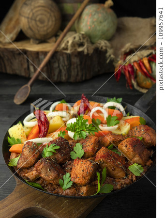 Stew with meat and vegetables in black iron dish. Traditional gourmet goulash in a rustic kitchen 109957641