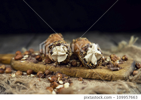 Cannoli, deep fried Italian pastry tubes with a sweet ricotta cheese, chocolate chips and hazelnuts served on a wooden board Cannoli, deep fried Italian pastry tubes with a sweet ricotta cheese, chocolate chips and hazelnuts served on a wooden board 109957663