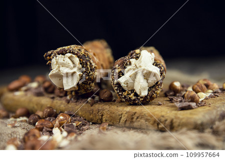 Cannoli, deep fried Italian pastry tubes with a sweet ricotta cheese, chocolate chips and hazelnuts served on a wooden board 109957664