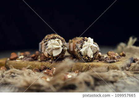 Cannoli, deep fried Italian pastry tubes with a sweet ricotta cheese, chocolate chips and hazelnuts served on a wooden board 109957665