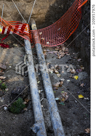 Pipeline reparation and reconstruction in the trench surrounded with orange safety net Pipeline reparation and reconstruction in the trench surrounded with orange safety net 109957976