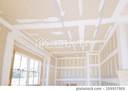 Finishing plastering drywall in ready to paint with new house under construction 109957988