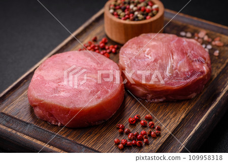 Round shape steaks of raw juicy tuna with salt and spices 109958318
