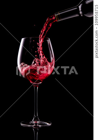 Red wine pouring into glass isolated on black background. Rose wine splashing in glassware. 109958715