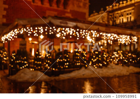 Decorative outdoor string lights at night time. Blurred background of outdoor restaurant with abstract bokeh light during Christmas holidays of night festival..  109958991