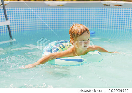 Boy relaxing on inflatable ring floating in pool have fun during summer vacation Boy relaxing on inflatable ring floating in pool have fun during summer vacation 109959913