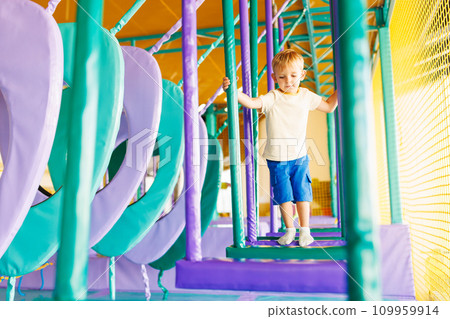 Cute little boy crawling and playing on colorful playground at amusement park Cute little boy crawling and playing on colorful playground at amusement park 109959914