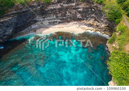 Cliff broken by wave of ocean formed perfect paradise untouched beach. Natural azure bathing pool in the rock. Angel's Billabong is popular tourist destination on island of Nusa Penida in Indonesia. 109960100