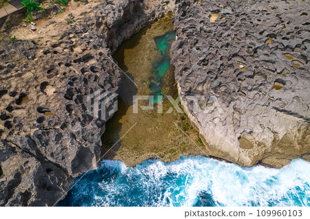 A cliff broken by the wave of the ocean. Natural azure bathing pool in the middle of the rock. A popular tourist spot on the island of Nusa Penida in Indonesia. A cliff broken by the wave of the ocean. Natural azure bathing pool in the middle of the rock. A popular tourist spot on the island of Nusa Penida in Indonesia. 109960103