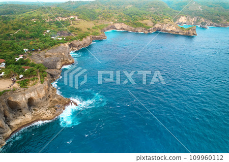 Cinematic aerial landscape shots of the beautiful island of Nusa Penida. Huge cliffs by the shoreline and hidden dream beaches with clear water. 109960112