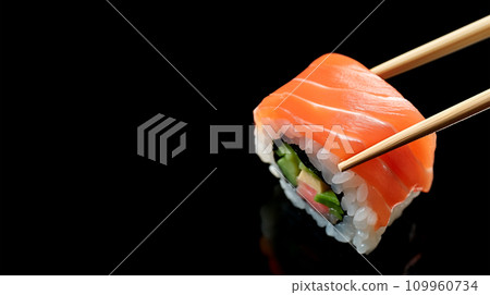 AI-generated content. Chopsticks hold Philadelphia sushi roll with salmon, black background with copy space. AI generated AI-generated content. Chopsticks hold Philadelphia sushi roll with salmon, black background with copy space. AI generated 109960734