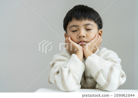 A 7-year-old boy resting on his chin and closing his eyes 109962844