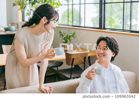 A young Japanese couple who are close friends having a conversation on the sofa in the living room of their house 109963042