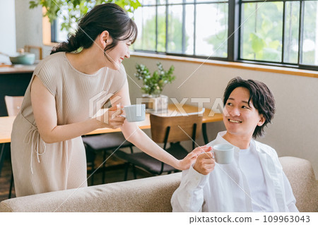 A young Japanese couple who are close friends having a conversation on the sofa in the living room of their house 109963043