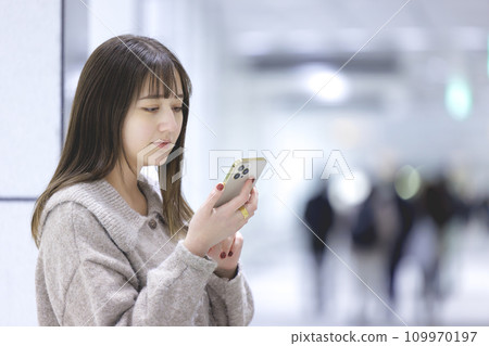 A young woman operating a smartphone 109970197