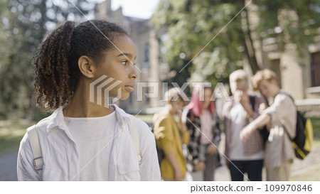 African American girl listening to her classmates discussing her appearance, bullying 109970846