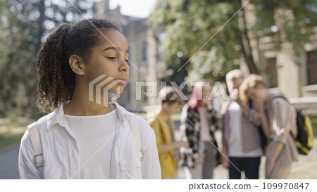 Group of children gossiping about African American school mate, bullying, abuse Group of children gossiping about African American school mate, bullying, abuse 109970847