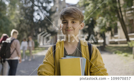 Nice middle school boy smiling on camera, holding books, ready for classes 109970857