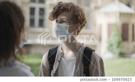 School boy and girl in medical face masks communicating after classes, epidemic School boy and girl in medical face masks communicating after classes, epidemic 109970923