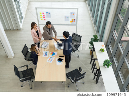 A group of business professional are in an office, engaging in a firm handshake following a successful meeting or agreement. A group of business professional are in an office, engaging in a firm handshake following a successful meeting or agreement. 109971643