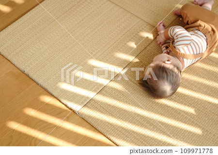 Baby lying down and playing on the tatami 109971778