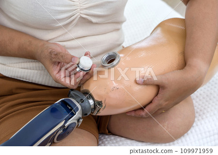 Determined woman expertly navigating a high-tech device on her leg, suggesting healthcare tech use. Determined woman expertly navigating a high-tech device on her leg, suggesting healthcare tech use. 109971959