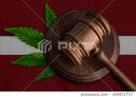 Justice wooden gavel with cannabis leaf on the Flag of Latvia. Illegal growth of cannabis plant and drugs spreading Justice wooden gavel with cannabis leaf on the Flag of Latvia. Illegal growth of cannabis plant and drugs spreading 109972757
