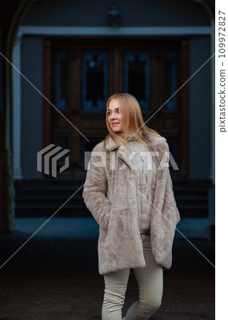Beautiful woman in light clothes and a fur coat on a city street. Winter season, walk in the city. Vertical frame 109972827