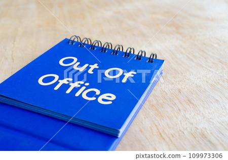 Out of office text on notepad on wooden table background. Out of office concept. 109973306