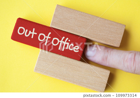 Finger pushing out red wooden block with out of office text on yellow cover background. Finger pushing out red wooden block with out of office text on yellow cover background. 109973314