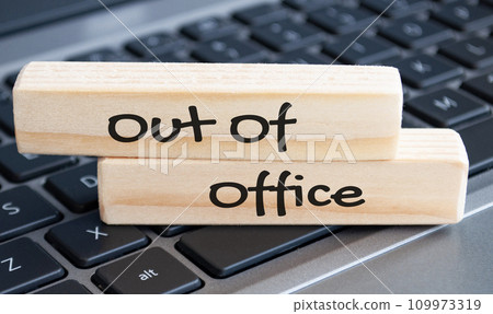 Out of office text on wooden blocks with laptop background. Out of office concept. Out of office text on wooden blocks with laptop background. Out of office concept. 109973319